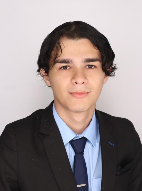 Man with dark hair wearing a suit and tie