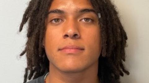 Gabriel Effiong with dark locs and a grey shirt, in front of a light grey background