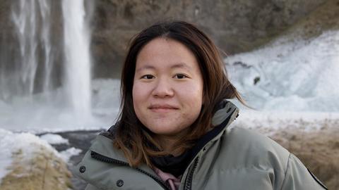 Woman in a coat standing in front of a waterfall