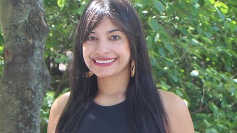 Portrait of Wendy Valencia-Montoya, woman with long dark hair wearing a black top and standing outside