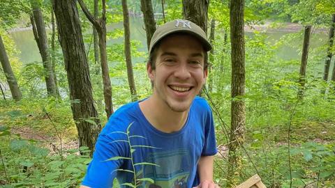 Graduate student Patrick McKenzie working outdoors with plants