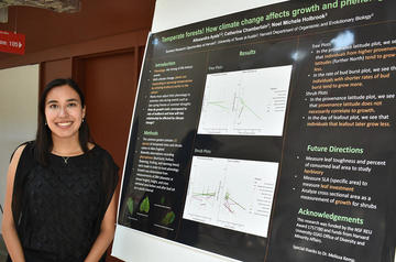 Woman in black top standing in front of a poster