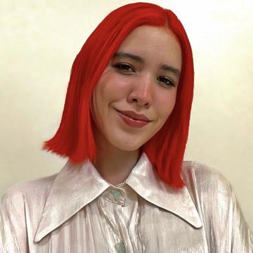 Woman with red hair and white top standing in front of a wall