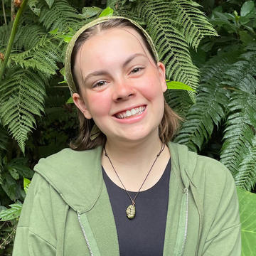 Woman in a green sweatshirt standing in front of a tree