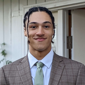 Man wearing a suit and tie standing in front of a house