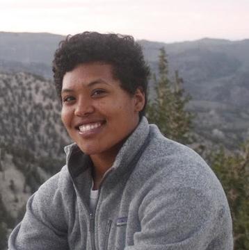 Person in a gray fleece sitting on top of a hill