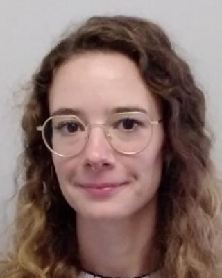 Cecilia Trivellin with long wavy light hair and glasses, in front of light grey background