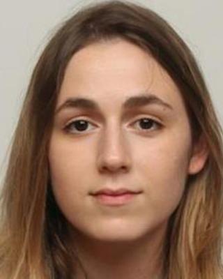 Daniella Haber, with long light brown hair, in front of a light grey background