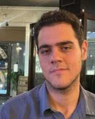 Mahdiyar Shahbazi with short brown hair and blue shirt, in front of display cases
