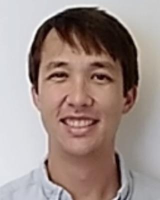 Paul Bump with short dark hair and light button-down shirt, in front of white background
