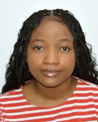 Akosua Nyame with long, dark hair and a red and white striped top, in front of light grey background