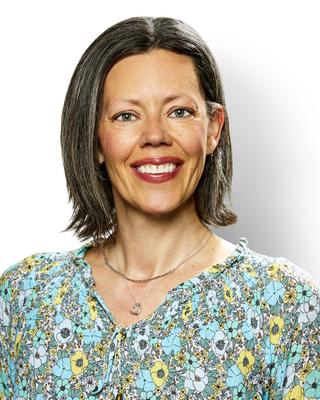 Jesselynn Opie with medium brown hair in flowered blouse, white background