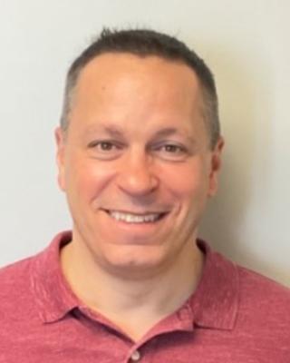 Portrait of Anthony Manita. Person with short dark hair wearing a red shirt