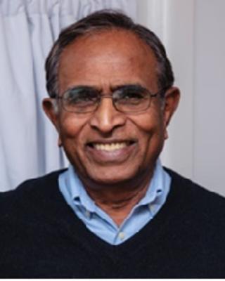 Portrait of Diddahally Govindaraju. Man wearing glasses, a black sweater with blue oxford shirt, smiling