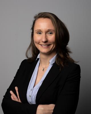 Portrait of Kim Kirchhoff with arms crossed, smiling, waring a black blazer