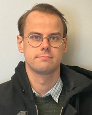 Portrait of postdoc Emil Warnberg wearing glasses and a black jacket