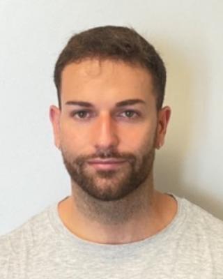 Portrait of postdoc Esteban Ramirez Chueca with a beard wearing a white shirt