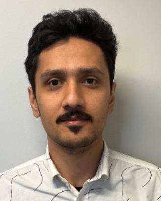 Portrait of postdoc Krishna Rijal wearing a white shirt with dark hair and mustasche