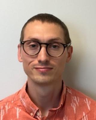 Portrait of postdoc Trey Scott wearing glasses and an orange print shirt
