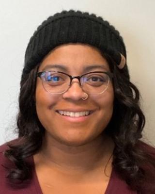 Portrait of postdoc Victoria Watson-Zink wearing a black hat and glasses