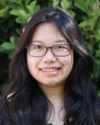 Portrait of graduate student Guo Cheng with long dark hair wearing glasses and standing outside