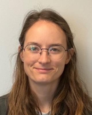 Portrait of postdoc Sarah Frail with long brown hair wearing glasses