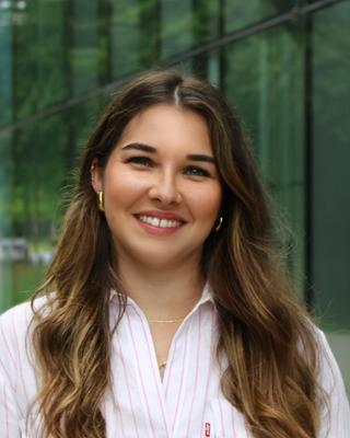 Portrait of postdoc Emilie Isasa standing in front of a building wearing a stripped shirt