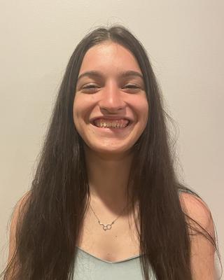 Woman with long dark hair wearing a green top and smiling