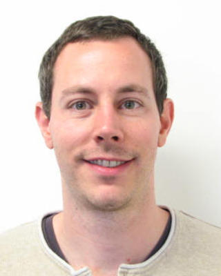 Andreas Kautt with short brown hair, wearing a beige shirt, in front of a white background