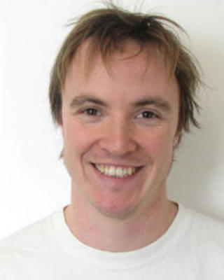 Connor White with short light brown hair, wearing a white shirt, in front of a white background