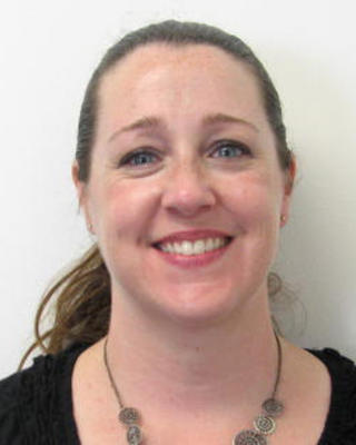Erin Ciccone smiling, long light brown hair pulled back, black shirt, white background