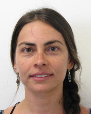 Flavia Termignoni Garcia with brown hair in a long braid, in front of white background