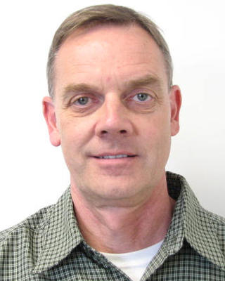 Fred Lindberg with short light hair, green checked shirt, light grey background