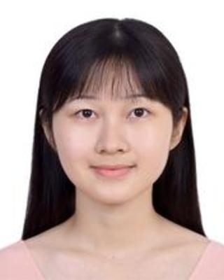 Honghao Song with long dark hair and bangs, wearing a light pink top, in front of a white background