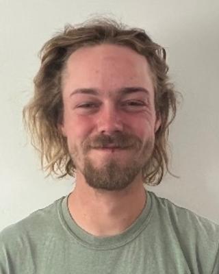 Ian Hughes iwth dark blond hair and beard, wearing a light green shirt, in front of a light grey background