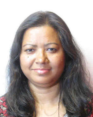Manju Barua with long dark hair, black and red top, and white background