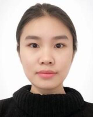 Maoting Chen with dark hair pulled back, wearing a black sweater, in front of a white background