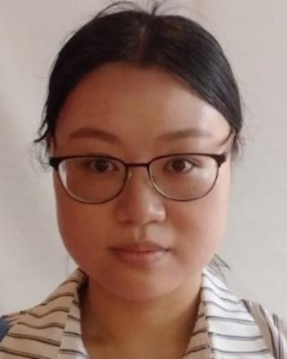 Min Wu, with dark hair pulled back, glasses, and a striped shirt, in front of a light grey background