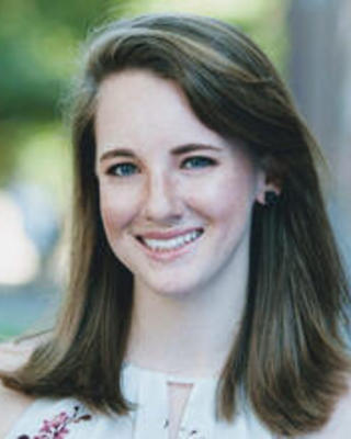 Rachel Harris with long light brown hair, light sleeveless shirt, leafy background