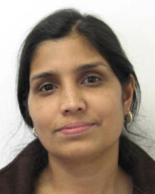 Tulika Deb with dark hair pulled back, dark brown fleece, white background