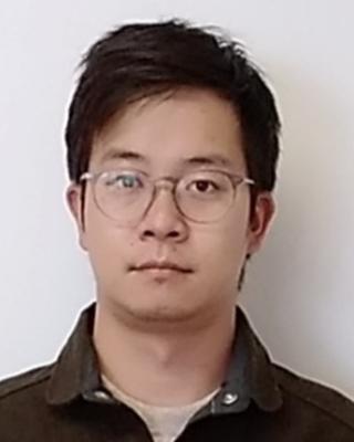 Yan Gong with short dark hair, wireframe glasses, and dark, collared shirt