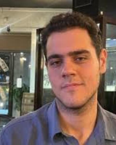 Mahdiyar Shahbazi with short brown hair and blue shirt, in front of display cases