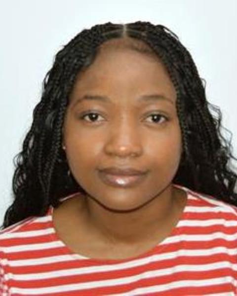 Akosua Nyame with long, dark hair and a red and white striped top, in front of light grey background