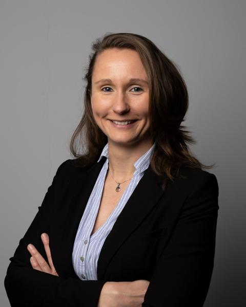 Portrait of Kim Kirchhoff with arms crossed, smiling, waring a black blazer