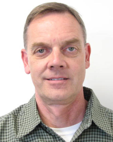 Fred Lindberg with short light hair, green checked shirt, light grey background