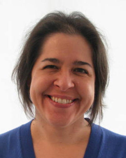 Julie Knippa Colby smiling, with medium-length dark hair, blue sweater, white background
