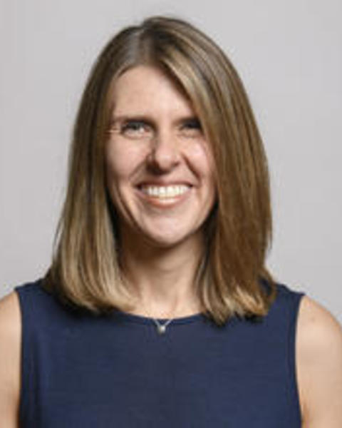 Kristin Pennarun with long dark blond hair, sleeveless blue top, light grey background