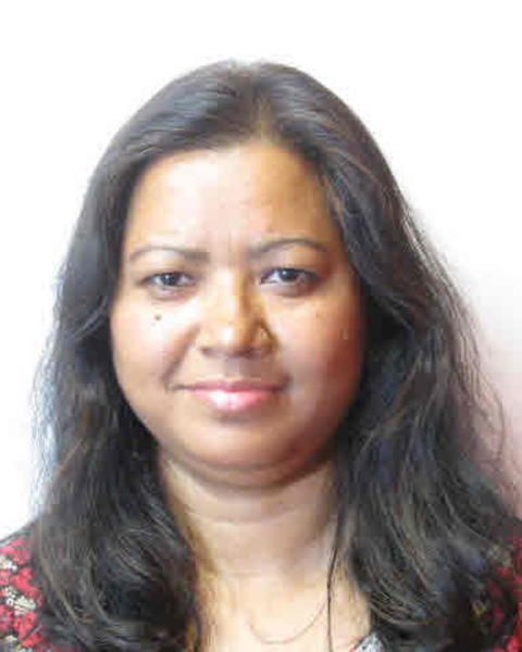 Manju Barua with long dark hair, black and red top, and white background