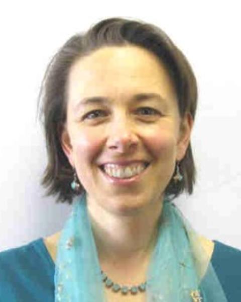 Sarah J Kariko with chin-length light brown hair, wearing a teal shirt and scarf, in front of a white background