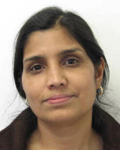 Tulika Deb with dark hair pulled back, dark brown fleece, white background